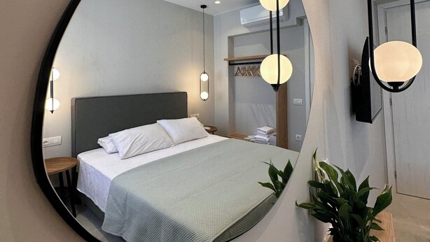 Een slaapkamer met een grote spiegel, een bed, nachtkastjes en een potplant.