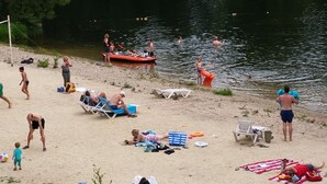 A beach with people sunbathing, swimming, and playing. - Camping Les Vignes (Puy-l'Eveque)