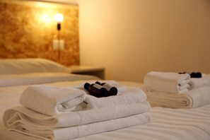 A neatly made bed with folded white towels and a bottle of lotion. - Ambarabà B&B (Naples)