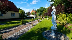 A garden with a statue, a house, and a well-maintained lawn.