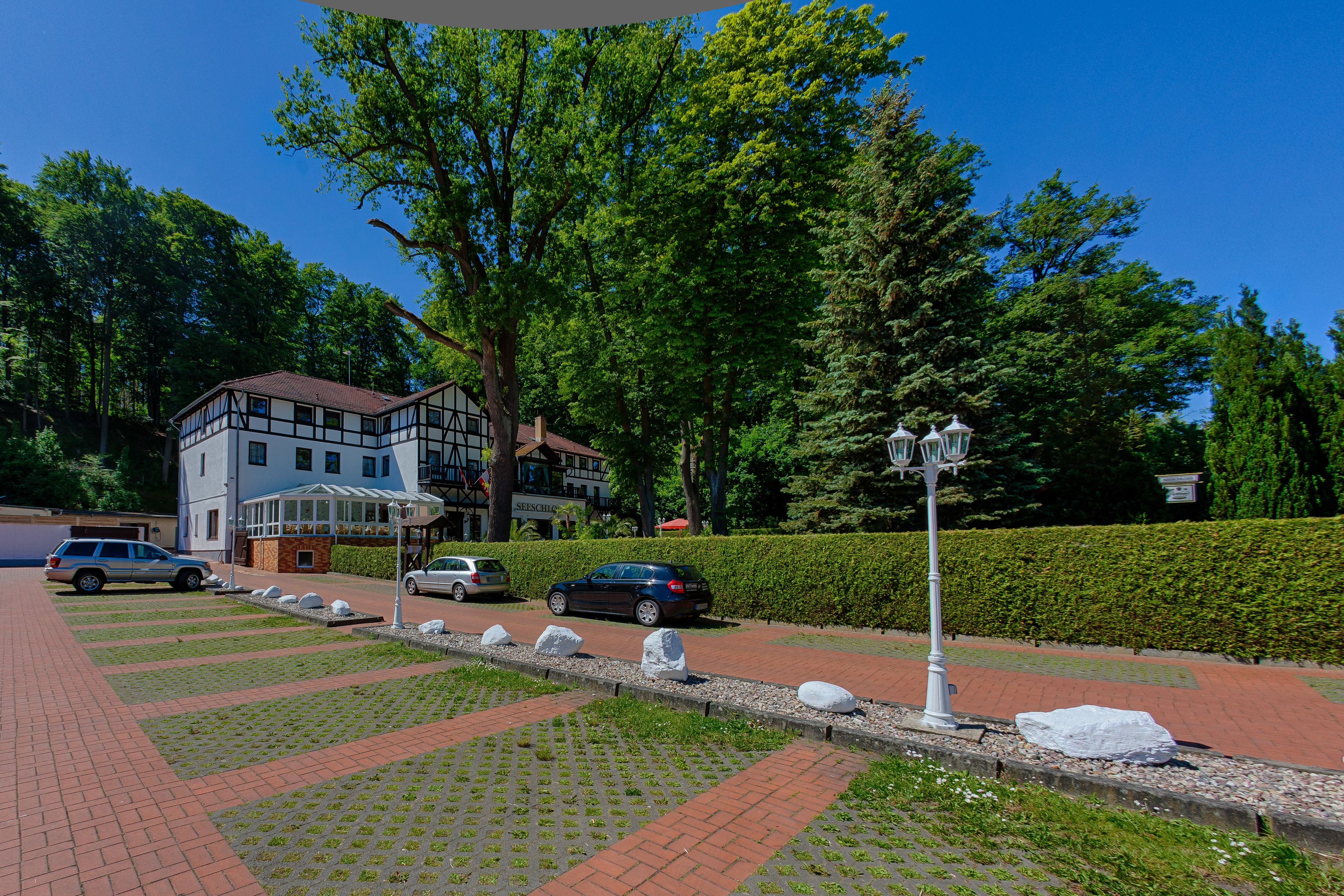 A paved pathway with a row of white bollards, a building with a traditional facade, and a hedge in the background.
