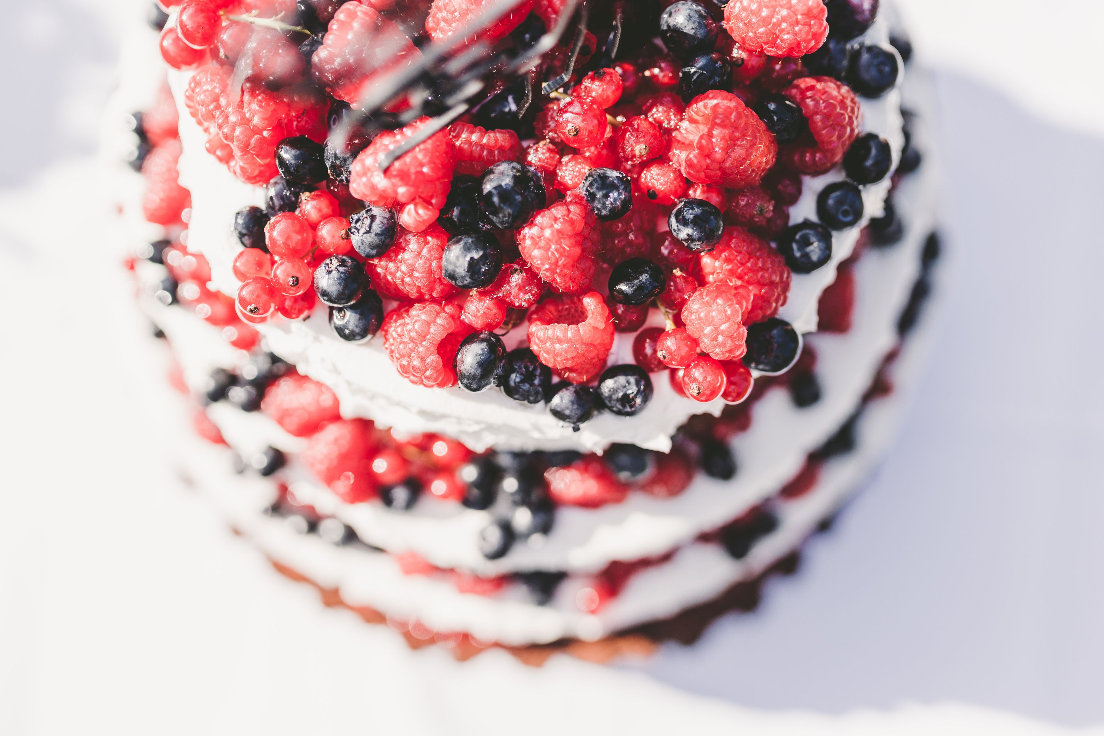 A layered cake with multiple tiers, each adorned with red and black berries.