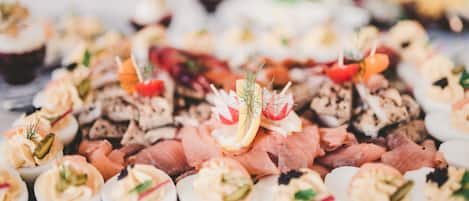 Una variedad de aperitivos, entre ellos huevos rellenos, salmón ahumado y canapés, sobre una bandeja.