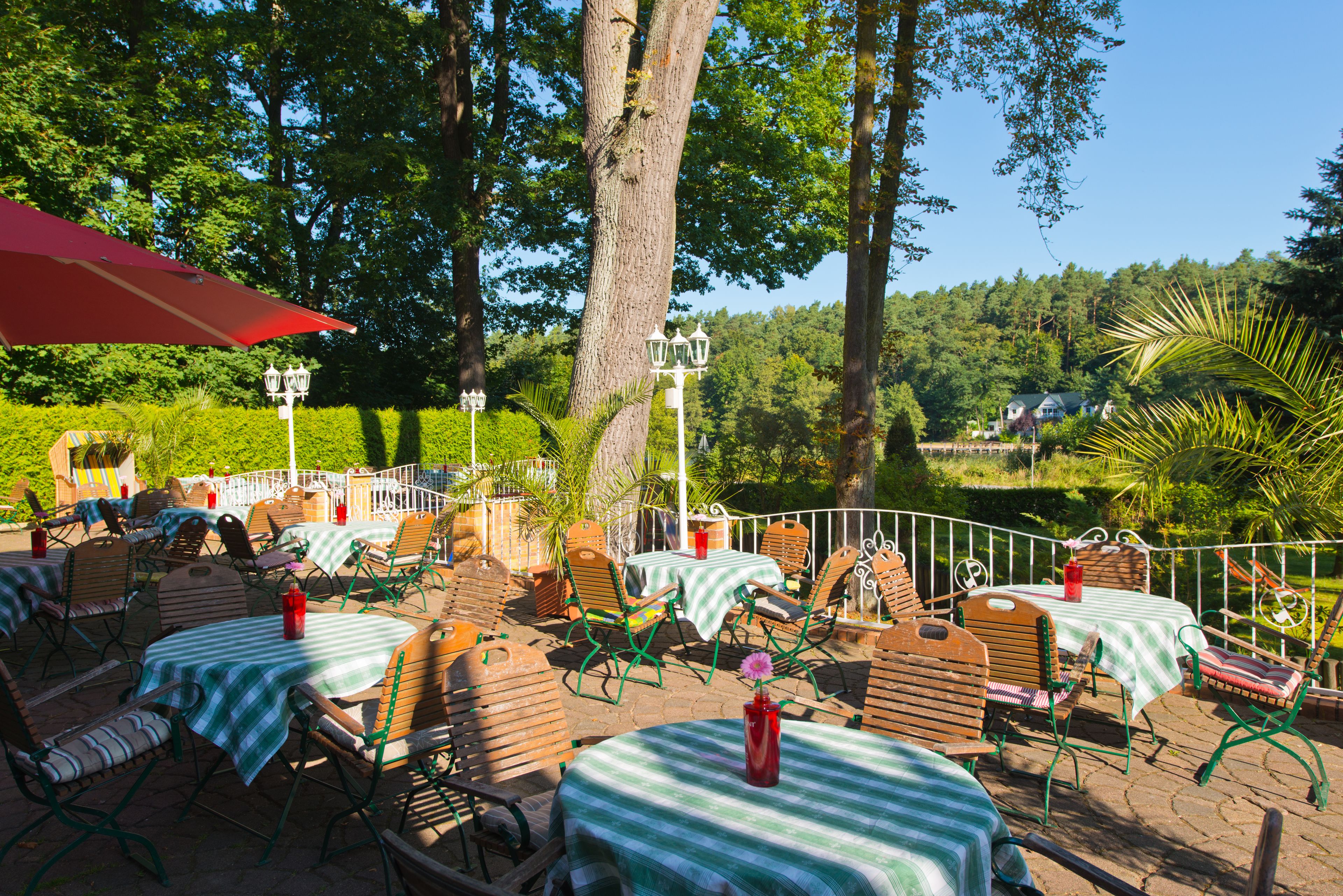 An outdoor patio area with tables and chairs, surrounded by trees and greenery.