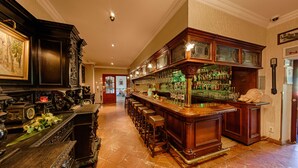A bar area with a long counter, stools, and a variety of bottles and glasses.