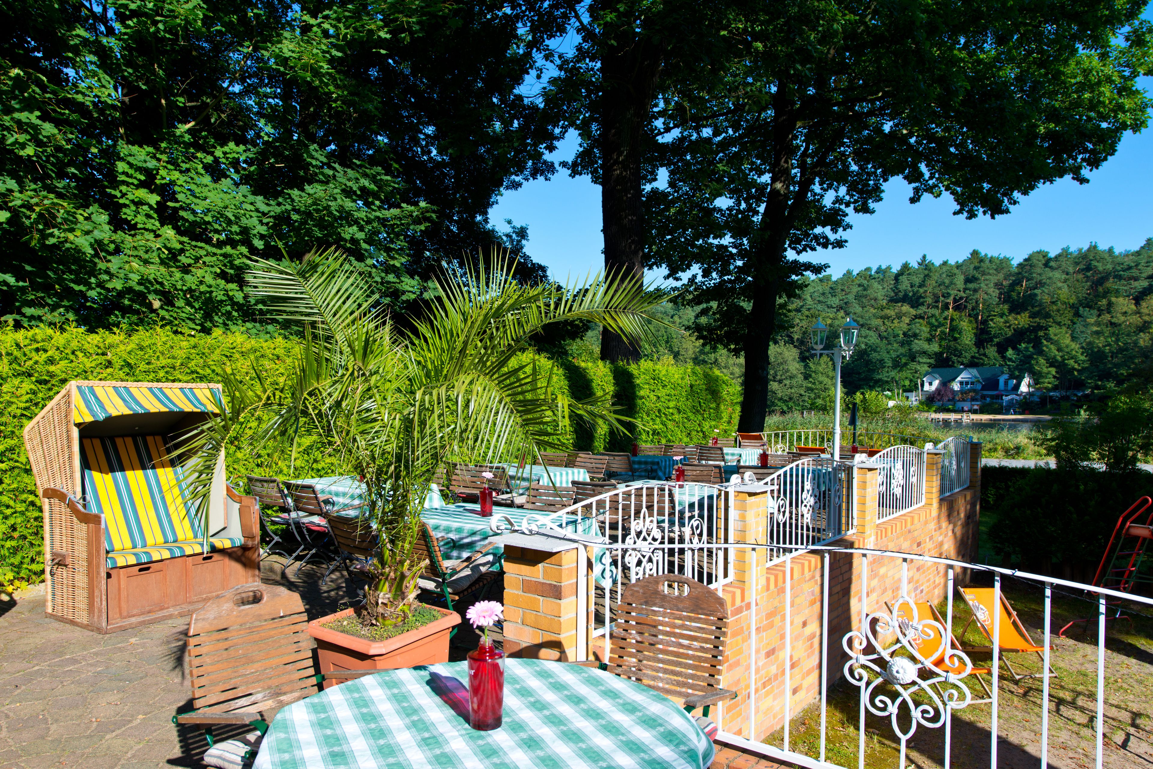 A patio area with outdoor seating, a small table with a vase, and a view of a forested area.