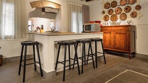 A kitchen with a central island, bar stools, a microwave, and a wooden cabinet. - Biennale Garden Art & Architecture Venue (Venice)