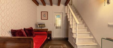 A staircase leading to a landing with a bed and a small table with a lamp.