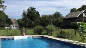 Une piscine rectangulaire à l’eau d’un bleu limpide, entourée d’une terrasse en bois et d’une pelouse.
