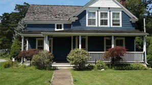 Une maison à deux étages avec un porche à l’avant, un chemin menant à l’entrée et une pelouse bien entretenue.