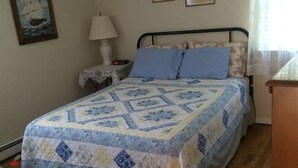 Une chambre à coucher avec un lit, une table de chevet, une lampe et deux tableaux encadrés accrochés au mur.