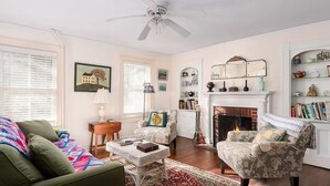 Un salon avec une cheminée, un ventilateur de plafond et une bibliothèque.