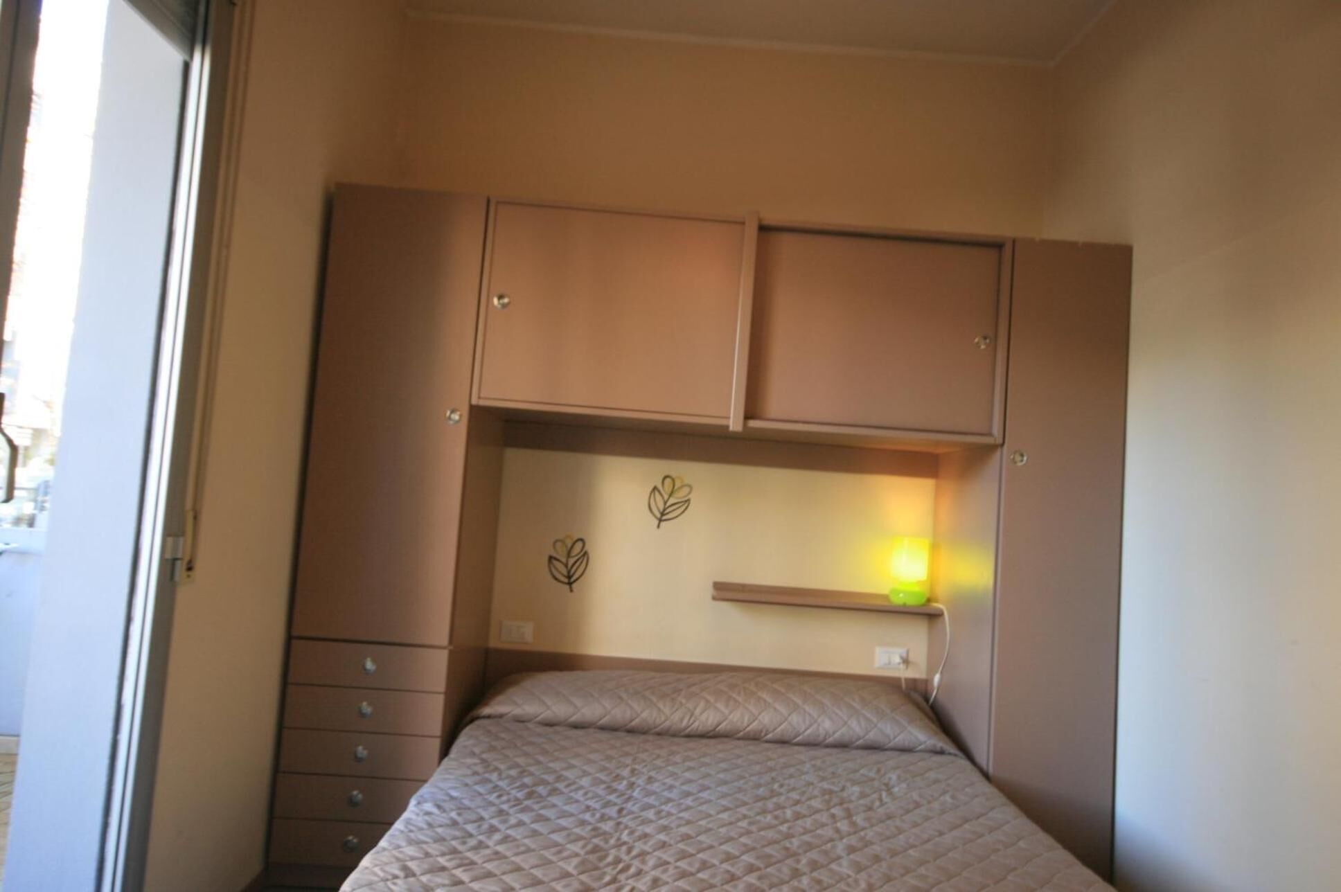Een slaapkamer met een bed, een dressoir en een nachtkastje.