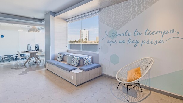 A modern interior with a seating area, a large window, and a wall with a motivational quote. - One Puebla Angelópolis Periférico (San Andrés Cholula)