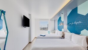 A modern hotel room with a large bed, a television, and a view of the city through a window. - One Puebla Angelópolis Periférico (San Andrés Cholula)