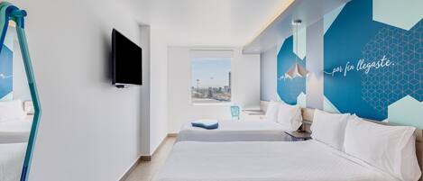 Une chambre d’hôtel moderne, dotée d’un grand lit, d’une télévision et offrant une vue sur la ville par une fenêtre.