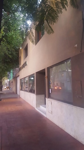 A building with large windows and a tree in front. - Hotel Universal (Mendoza)