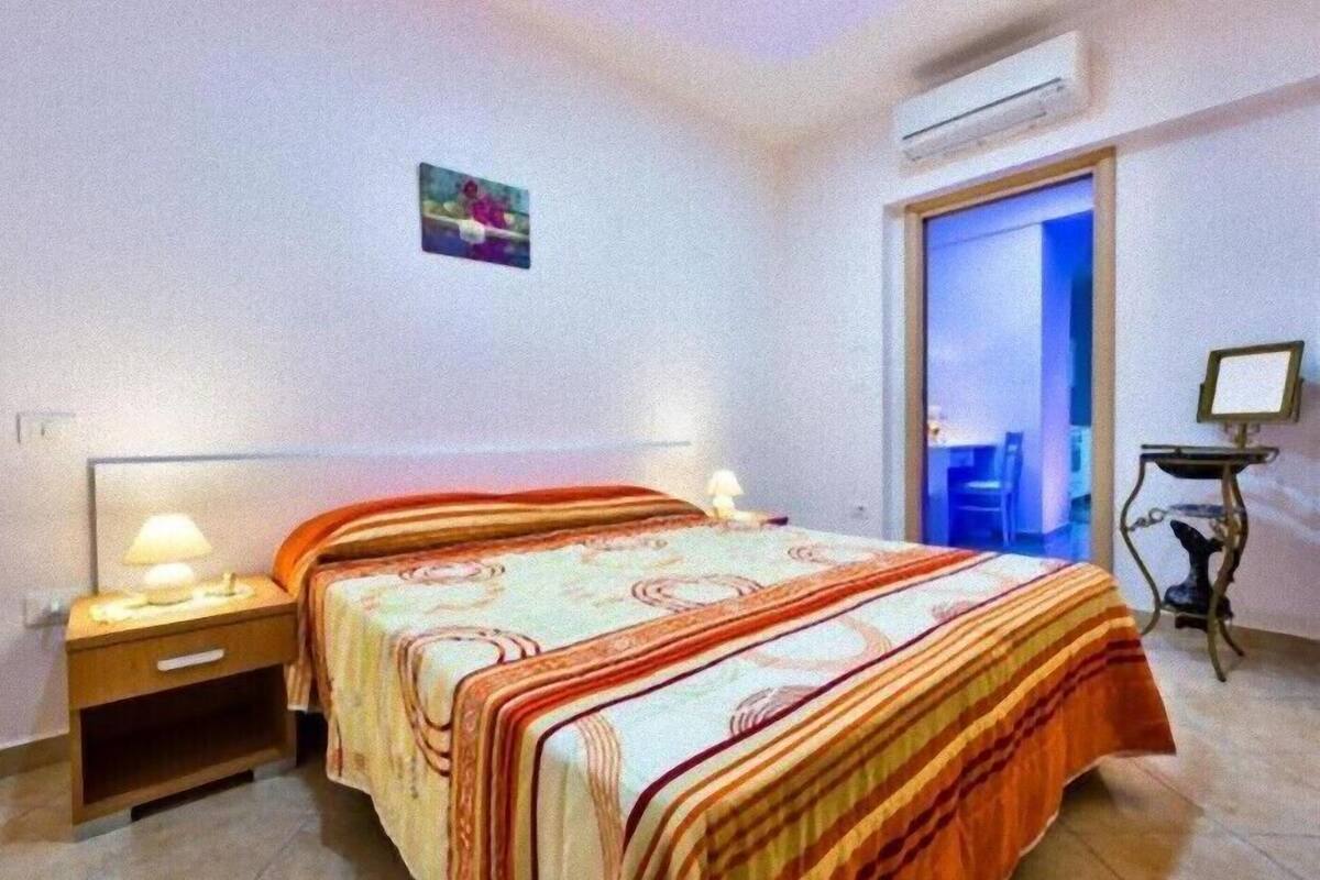 Ein Schlafzimmer mit Bett, Nachttisch, Lampe und einem kleinen Schreibtisch mit Stuhl.