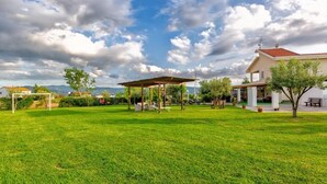 Un vaste espace extérieur agrémenté d’une pergola en bois, d’une pelouse bien entretenue et d’un bâtiment doté d’un toit rouge.