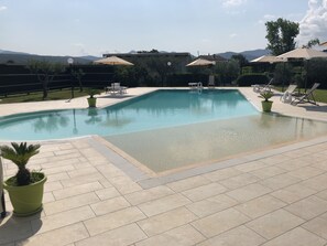 A swimming pool with a tiled deck, lounge chairs, and umbrellas. - Country House Jamm Jà (Capaccio-Paestum)