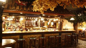 A bar with a brick counter, multiple stools, and a variety of bottles. - AKZENT Hotel Zur Post (Tabarz)