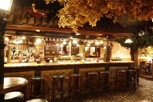 A bar with a brick counter, multiple stools, and a variety of bottles.