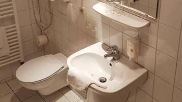 A bathroom with a toilet, sink, and mirror.