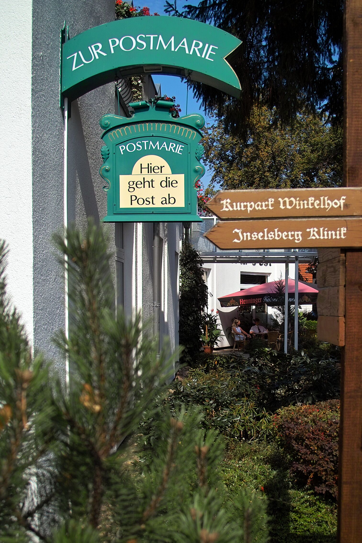 A signpost with 'Zur Postmarie' and 'Kurpart Winthelhof Innselsberg Klinit' directions.