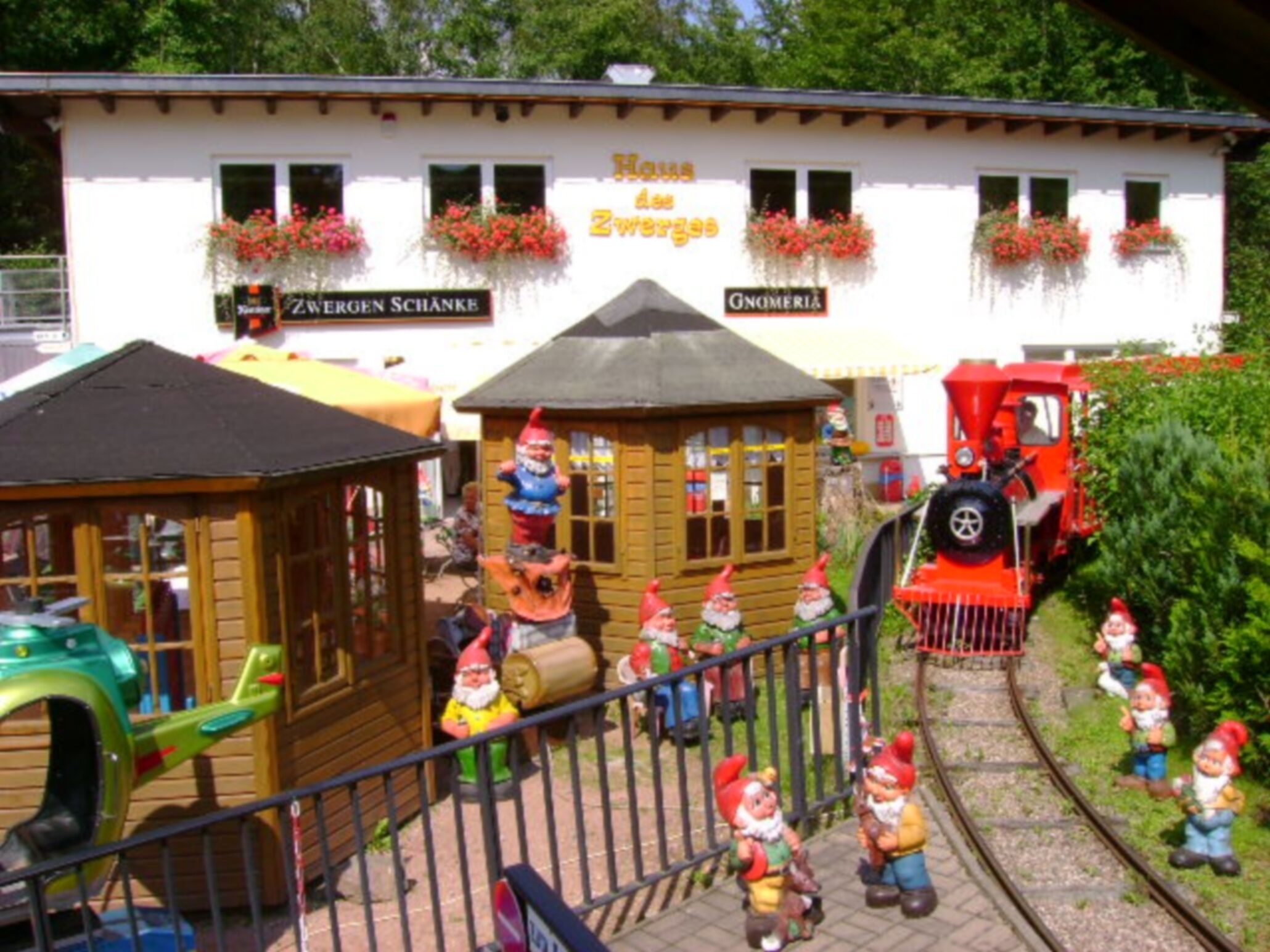 A model train setup with gnome figures and a small wooden structure.