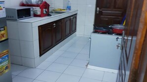 Una cocina compacta con paredes de azulejos blancos, un microondas, una cafetera roja y un refrigerador pequeño.