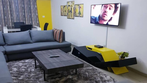Una sala de estar moderna con un sofá seccional, una mesa de centro y un televisor montado en la pared.