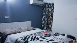 Un dormitorio con una cama, pared azul, aire acondicionado y cortina estampada.