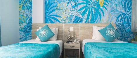 Habitación de hotel con dos camas, ropa de cama color turquesa, una mesita de noche con teléfono y un mural de hojas tropicales.