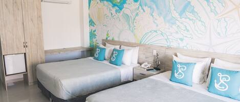 Habitación de hotel con dos camas, un armario de madera, un escritorio pequeño y un mural en la pared.