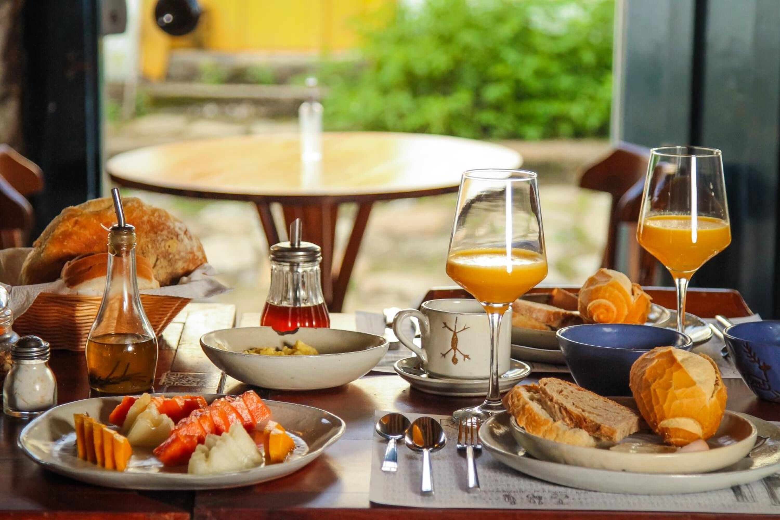 A breakfast table with various food items, a glass of orange juice, and a bottle of honey.