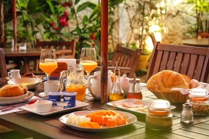 A breakfast table with plates of food, glasses of orange juice, and various condiments.