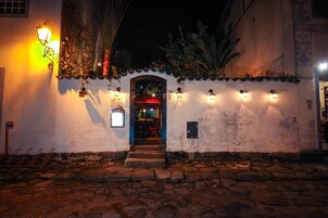 A building entrance with a stone-paved ground, a door with a red umbrella, and wall-mounted lights.