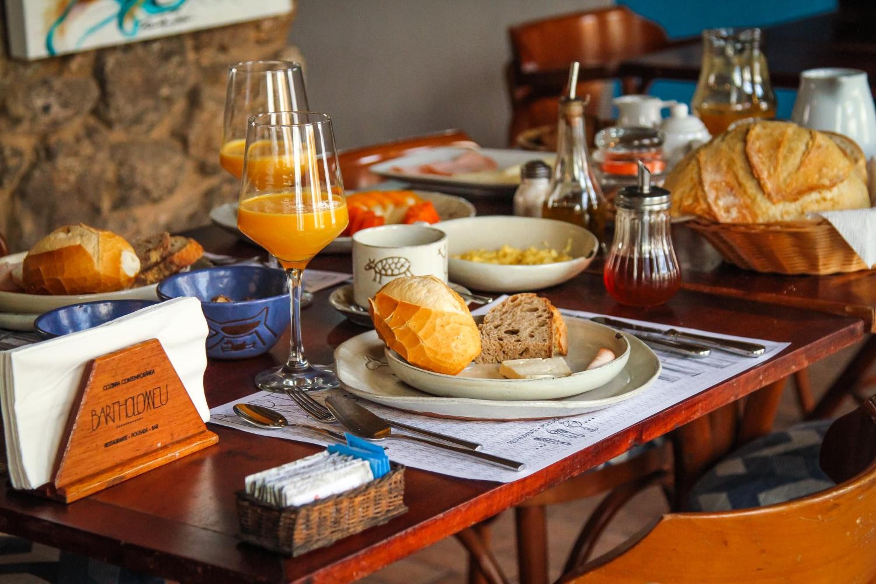 A breakfast setting with bread, orange juice, and a menu on a wooden table.