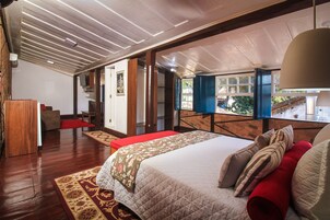 A spacious bedroom with a large bed, a red bench, and a view of a balcony.