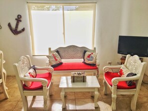 A living room with a sofa set, two armchairs, a coffee table, and a television. - Casa Marinera Gran Pacifica Resort (Villa El Carmen)