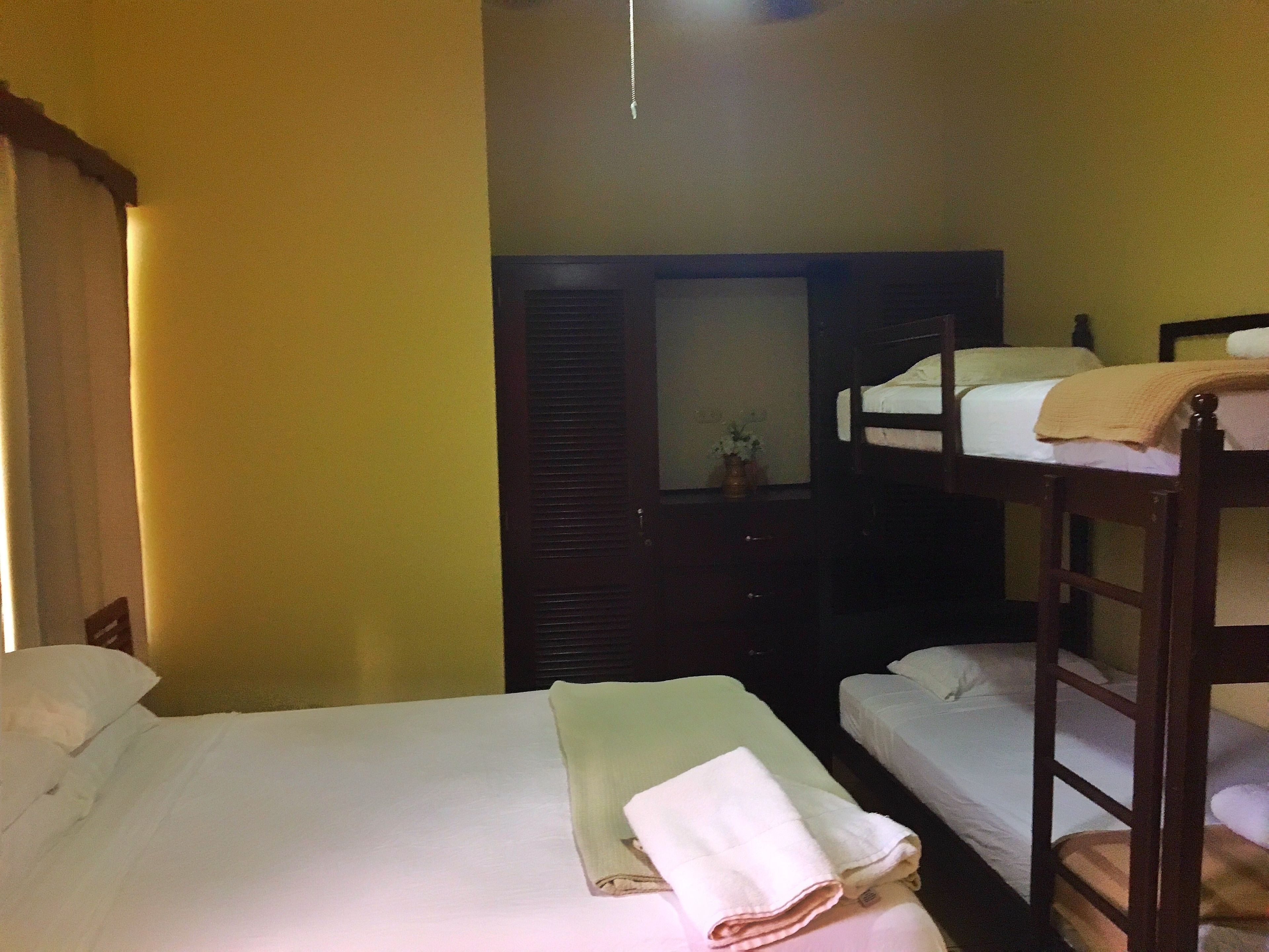 Una habitación con literas, un armario de madera y un espejo en la pared.