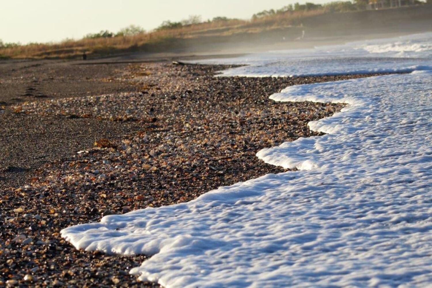 Une plage de galets où les vagues viennent lécher le rivage.