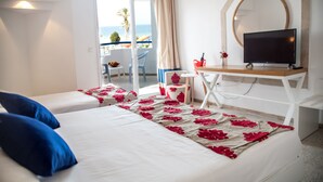 A hotel room with two beds, a TV on a desk, and a balcony with a view of the sea. - Palmyra Holiday Resort & Spa (Monastir)