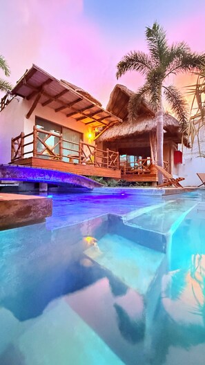 Un resort con piscina, una construcción de techo de paja y palmeras.