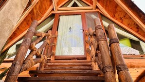 A wooden staircase leading to a room with a window, surrounded by wooden beams and a palm tree. - A&V Hotel Boutique (Coyuca de Benitez)