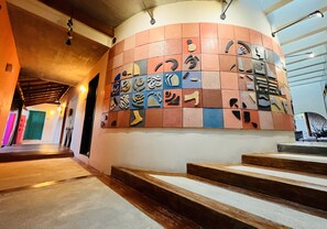 A hallway with a curved wall decorated with various symbols and a staircase leading to an upper level. - A&V Hotel Boutique (Coyuca de Benitez)