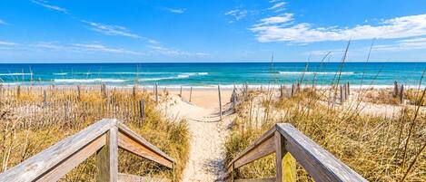 A wooden pathway leading to a beach with a clear view of the ocean.