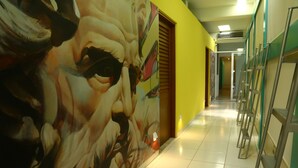 A hallway with a large mural, tiled floor, and metal handrails. - Hostel Tropico 20º OceanFront (Cozumel)