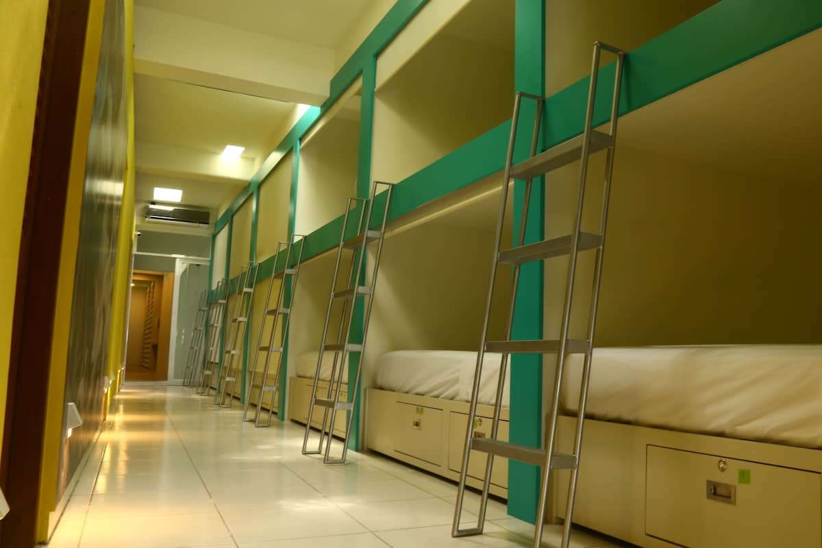 Pasillo con literas y escaleras, indicando un alojamiento tipo dormitorio.