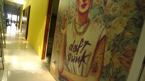 A corridor with a tiled floor and a large floral mural on the wall. - Hostel Tropico 20º OceanFront (Cozumel)